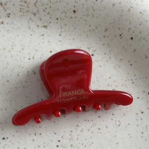Détail de la pince à cheveux rouge en acétate avec inscription dorée faite main