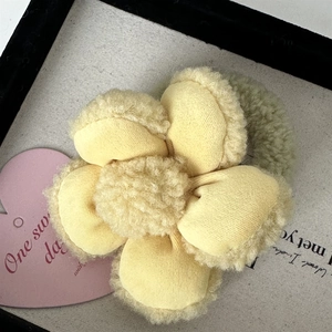 Détail macro d'un chouchou fleur en peluche avec pétales jaunes et élastique vert