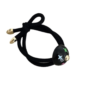 Elastic black nylon hair tie featuring a polished star-patterned ball and gold bead accent