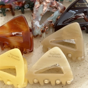 Detail showing various colors of French acetate triangular hair claws with marble texture