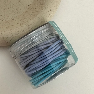 Morandi blauwe en groene elastische haarelastiekjes in een ronde plastic pot