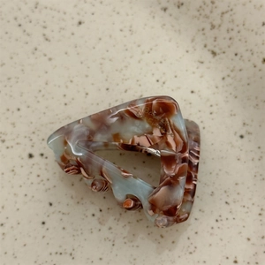 Detail of triangular acetate hair claw with blue-grey marble texture on ceramic base