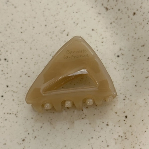 Macro detail of amber acetate triangular hair claw clip with Barrette la France logo