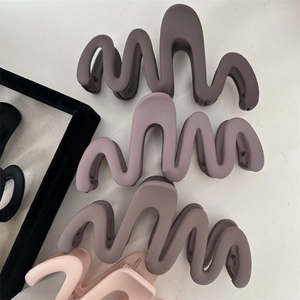 Dettaglio macro di grandi pinze per capelli a onde opache in vari colori Morandi