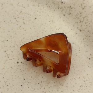 Macro detail of tortoiseshell acetate triangular hair claw clip with La France engraving