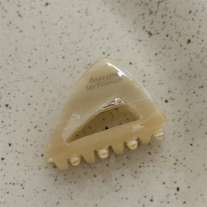 Detail view of a triangle acetate hair claw with Barrette la France print and marble pattern