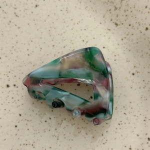 Detail showing marble texture acetate hair claw with gold lettering and spring design