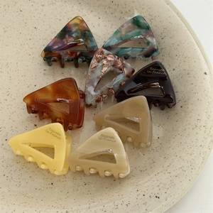 French acetate triangle hair clips in tortoiseshell and marble patterns set in a ceramic bowl