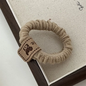Detail view of khaki scrunchie with high elasticity and cute bear head leather patch