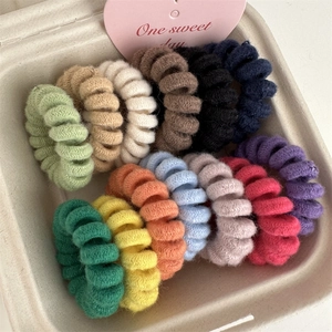 Detail of 13 candy-colored fuzzy spiral hair ties presented in a heart-decorated gift box