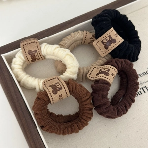 Close-up of five elastic hair scrunchies with cute bear tags in earthy tones for women