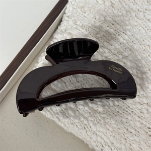Detailed close-up of dark brown acetate hair claw clip with golden French lettering