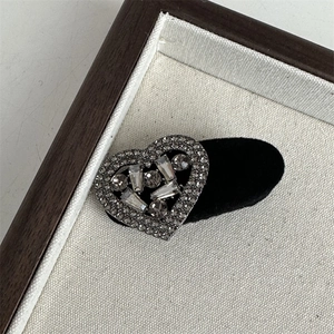 Macro shot of a black velvet heart hair clip with luxury rhinestones on a canvas tray