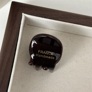 Macro-opname van een mini haarclip van acetaat met een gouden handgemaakte inscriptie