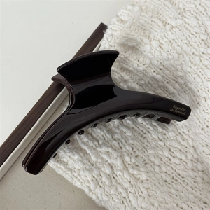 Detailed macro view of dark brown acetate hair claw clip with golden lettering