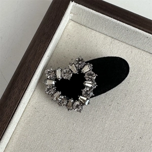 Detail of grey crystal heart hair clip with square rhinestones on elegant wooden tray