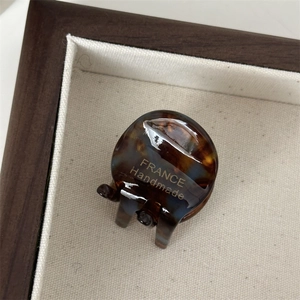 Detail van een schildpad haarklem met gouden France Handmade logo op een dienblad