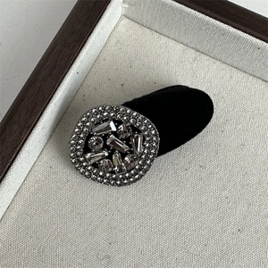 Macro detail of a velvet heart hairpin with sparkling square rhinestones on a tray