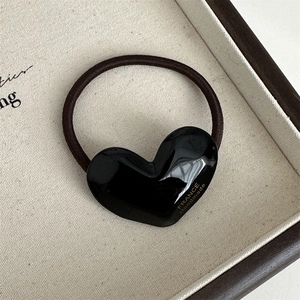 Detail of a black acetate heart hair tie with gold France Handmade lettering in a box