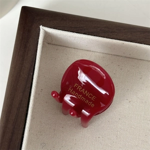 Detail van rode acetaat haarklem met gouden France Handmade belettering op display