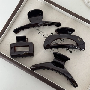 French vintage dark brown acetate hair claws displayed on a wooden tray with gold text