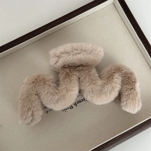 Détail de la pince à cheveux en peluche marron clair avec une texture ondulée