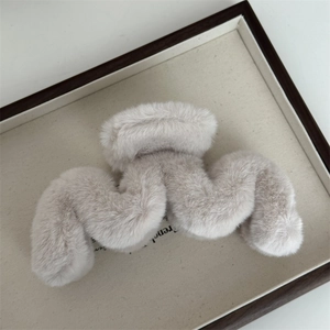 Détail d'une pince à cheveux en peluche douce couleur avoine sur plateau décoratif