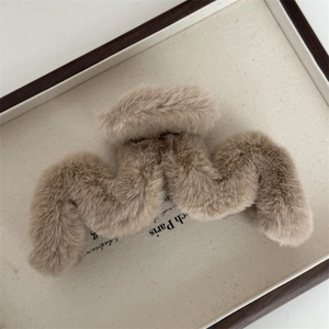 Gros plan d'une pince à cheveux en peluche marron clair dans un plateau, accessoire d'hiver