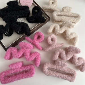 Dettaglio di varie pinze per capelli in peluche rosa e neutro in forme geometriche