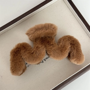 Détail d'une pince à cheveux vague en peluche marron terre avec texture douce