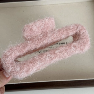 Primo piano di una pinza per capelli in peluche rosa con texture morbida e design rettangolare