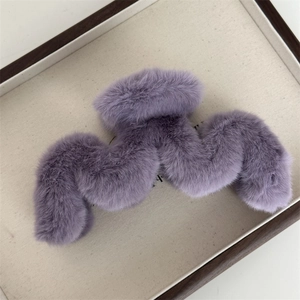 Gros plan détaillé sur une pince à cheveux en peluche violette sur un plateau beige