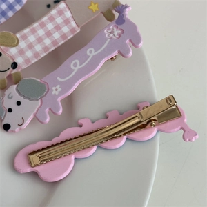 Détail de barrettes chiot mignon avec motifs floraux roses et violets sur une assiette en céramique