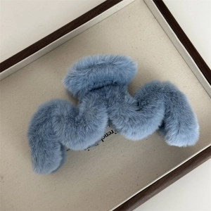 Détail d'une pince à cheveux en fausse fourrure bleue avec un design ondulé pour l'hiver