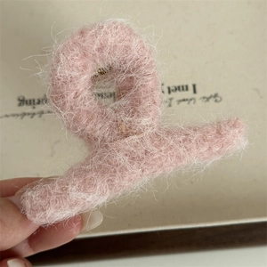 Dettaglio di una grande molletta per capelli rosa felpata con trama morbida e tessuta