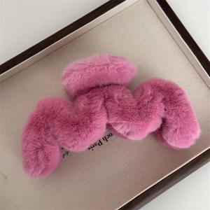 Détail de la matière en peluche rose et du design ondulé de la pince à cheveux en métal