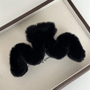 Détail macro de la pince à cheveux en fausse fourrure noire avec cadre géométrique