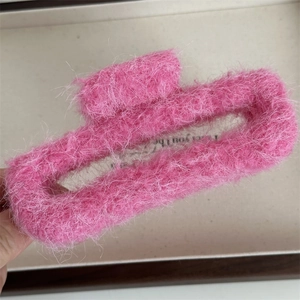 Dettaglio della pinza per capelli in peluche rosa con morbida texture in finta pelliccia