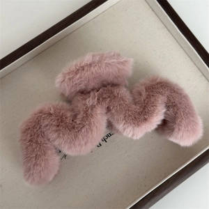 Gros plan sur la pince à cheveux en peluche rose avec dents ondulées sur plateau