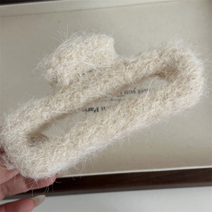 Primo piano di una grande molletta per capelli in peluche bianco crema morbido