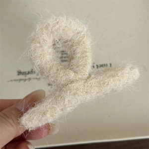 Dettaglio di una molletta per capelli in peluche beige con morbida consistenza in finta pelliccia