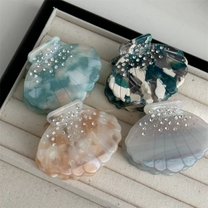Macro detail of shell-shaped acetate hair claws with sparkling rhinestone accents
