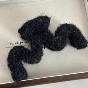 Dettaglio di una molletta per capelli in peluche nera ondulata con morbida finta pelliccia