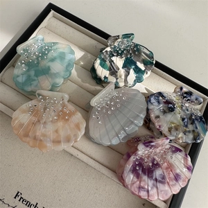 Scallop shaped acetate hair claws with rhinestones in various colors in a jewelry box