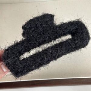 Dettaglio di una grande pinza per capelli in peluche nera con morbida finitura in pelliccia