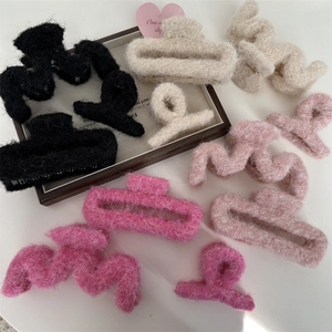 Dettaglio di fermagli per capelli in morbido peluche nei colori rosa, bianco e nero