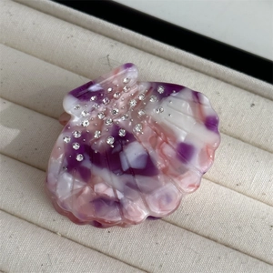 Detail of shell-shaped acetate hair claw with rhinestones and purple marble texture