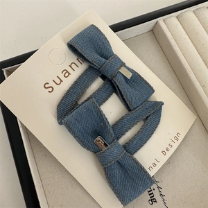 Detail von blauen Denim-Schleifen-Haarspangen mit gravierten Silberanhängern