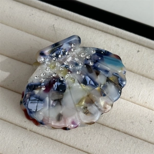 Macro shot of seashell hair claw made of colorful marbled acetate with sparkling rhinestones