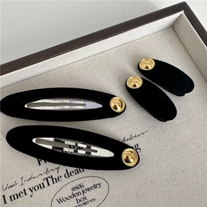 Retro black velvet hair clips set with gold metal accents in a vintage jewelry tray